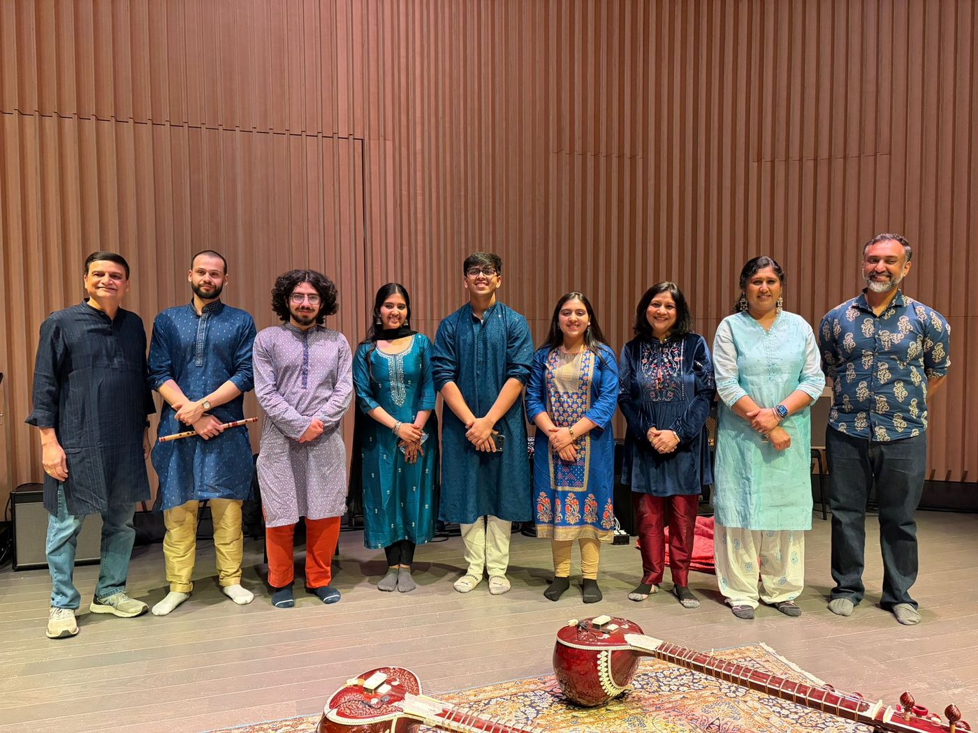 Kalaakaar Society artists standing together on stage with sitars in front of them