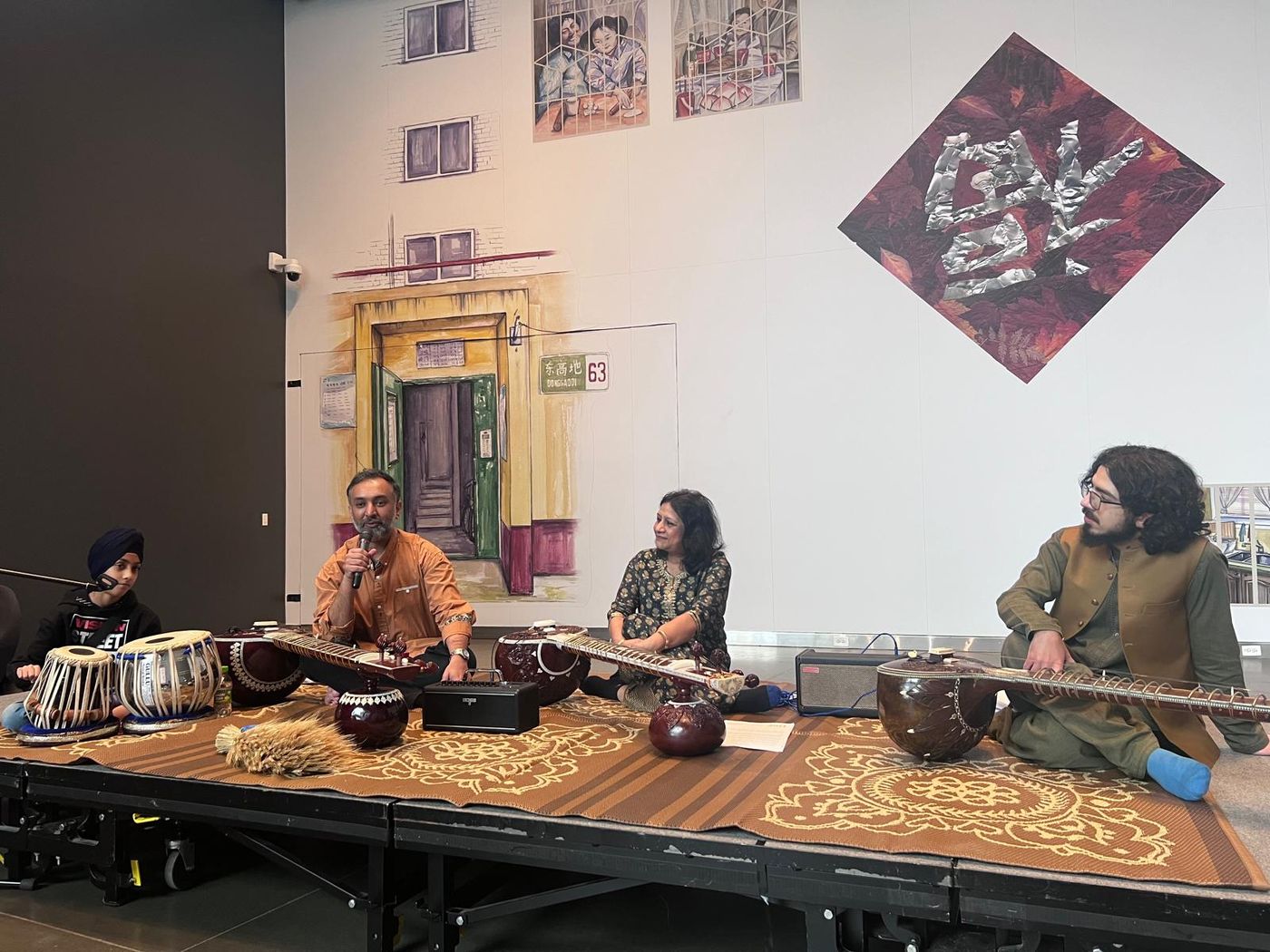 Tabla, sitar and vocalists performing in a gallery space with murals